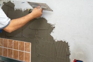 Spreading adhesive on concrete wall